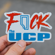 Sticker with red and blue text held by a hand against a blurred background