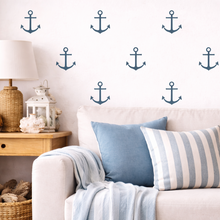 Living room with a beige sofa, blue and striped cushions, and decorative anchor wall decals.