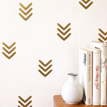 Decorative wall with gold arrow patterns and books on a shelf.