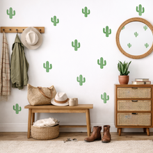 Nursery room with green cactus wall decals, wooden furniture, and decorative items.