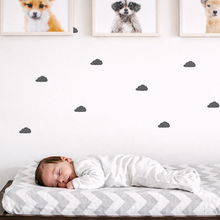 Child sleeping on a bed with a white and gray striped blanket, surrounded by framed pictures of dogs on a wall.