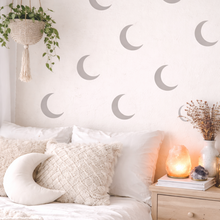 Bedroom with moon phase wall decals, plants, and a lit candle.