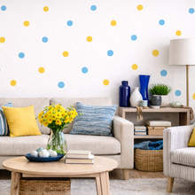 Living room with a beige sofa, colorful cushions, and a wall with polka dot patterns.