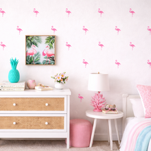 Children's room with flamingo wall decals, a dresser, and decorative items.