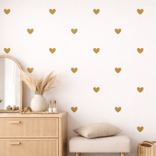 Room interior with gold heart decals on a white wall, wooden dresser, and decorative items.