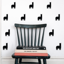 Black llama wall decals on a white wall with a black chair and books.