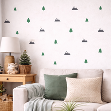 Living room with a white sofa, decorative pillows, and wall stickers of trees and mountains.