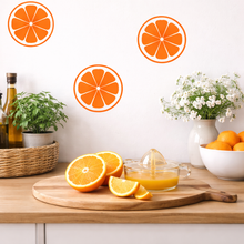 Kitchen counter with oranges, a juicer, and decorative elements on a white wall.