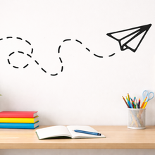 Desk with stationery items and a whiteboard with a paper airplane drawing.