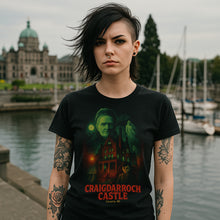Person wearing a black t-shirt with 'Craigdarroch Castle' design by a waterfront.