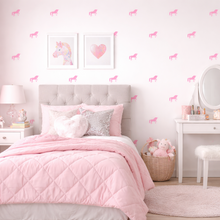 Pink-themed bedroom with unicorn and heart wall decals, bed, desk, and shelves.