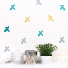 Decorative wall with colorful 'X' marks and a plant on a white surface.